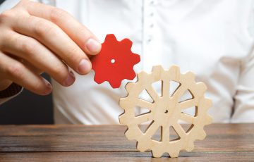 Businessman connects a small red gear to a large gear wheel. Symbolism of establishing business processes and communication. Increase efficiency and productivity. The best business formula for success